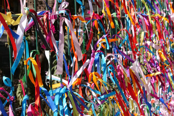Close up of colourful strings tied to a fence.  The background is intentionally out of focus or blurred.