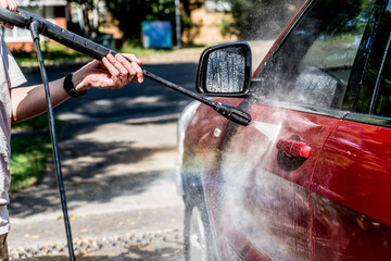 Selective focus shot of washing a red Suv 4wd car with high pressure washer cleaner. Car wash