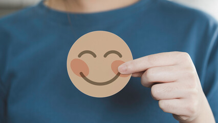 Hand holding nude color paper cut happy smile face on green blue background , positive thinking,...