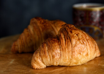 Fresh baked croissants on baking paper with espresso cup at background