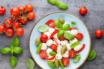 Delicious caprese salad with ripe cherry tomatoes and mini mozzarella cheese balls with fresh basil leaves.