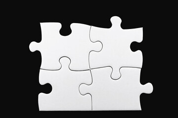 Obraz premium Four white puzzle pieces isolated on black background. Concept of teamwork, solving problems