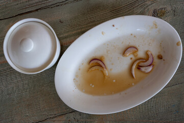 on a gray wooden table stands a white dirty plate a