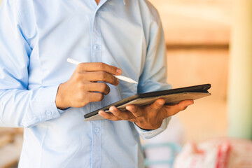 Young Asian foreman taking notes on his tablet, Business concept and technology.