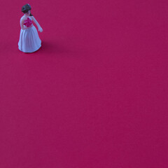 A girl with flowers in a white dress waiting on a red background with copy space. Minimal love scene.