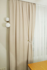 beige curtain folds and white tulle close up photo on window background