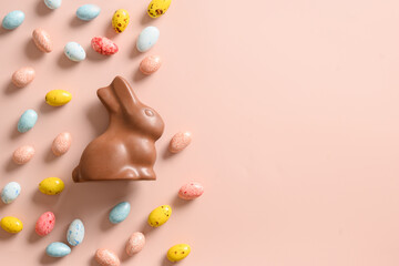 Easter banner with chocolate bunny and eggs on pink background. Space for text. View from above. Flat lay style. Happy Easter greeting card.