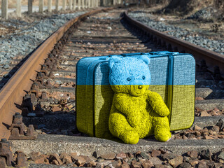 Koffer mit Bär auf Schienen in Ukraine Flagge
