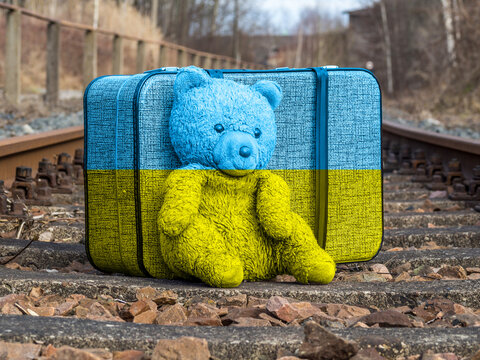 Koffer mit Bär auf Schienen in Ukraine Farben