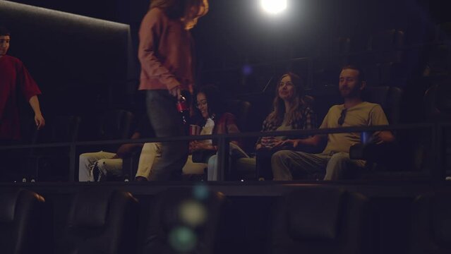 Group of young friends in a movie theater, came watching a movie on a big screen