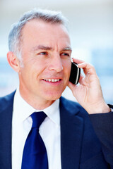 Executive discussing business deal. Man in suit smiling while talking on cell phone.