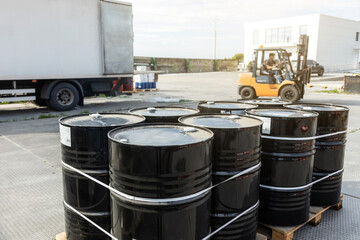 Black barrels with oil. Warehousing containers ready for shipment. Refining and selling oil...