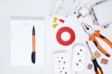  Electricity project in house. Top view different electrical tools, equipment and notebook with word plan.