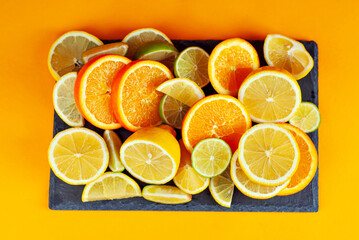 Oranges, lemons and limes cut into slices. Citrus vegetables on an orange background. Preparing vegetables for juice and cocktails.
