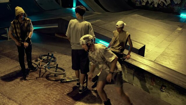 Young people finishing sport training at night skate park. Teens saying goodbye