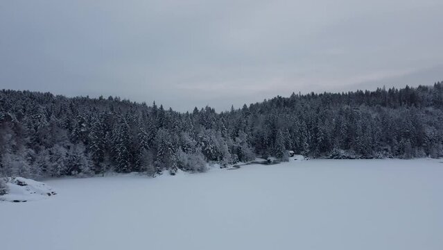 Flying towards the edge of Dingle Dam Snow Mountain Forest Cabin Sweden 4K 30fps