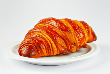 Yellow croissant in a plate isolated on a white background. Classic breakfast close up.