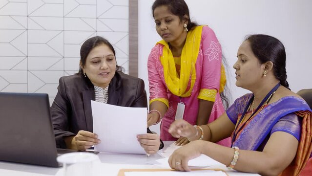 Handheld shot of group of woman employees discussing about project during meeting at office - concept of teamwork, cooperation support and planning business development.
