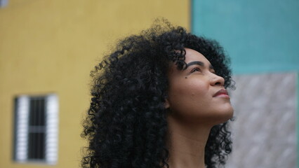 A latina black woman looking at sky with eyes closed feeling hopeful - obrazy, fototapety, plakaty