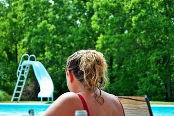 Over the shoulder of unrecognizable mother watching children in pool