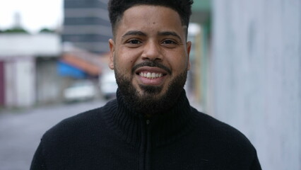 Fototapeta premium A diverse man walking forward toward camera smiling in urban sidewalk