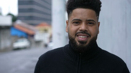 A diverse man walking forward toward camera smiling in urban sidewalk