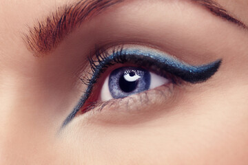 Obraz premium The eyes are the window to the soul. Close up of a blue eye with blue eyeliner.