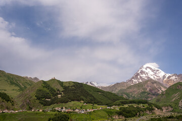 The mountain ranges of Georgia, Kazbegi, where two mountains form a triangular shape and above them a mountain spice that is covered with white snow