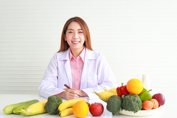 Beautiful Asian nutritionist sitting at her desk with fruits and vegetables she gave advice and prepare nutritious food Eat clean, healthy food. health care concept