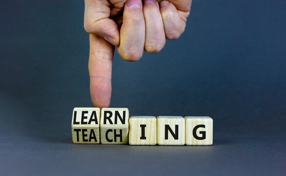 Learning or teaching symbol. Businessman turns wooden cubes and changes the word Teaching to Learning. Beautiful grey table grey background. Educational learning or teaching concept. Copy space.