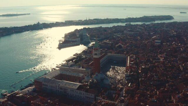 Circling drone shot against the sun of St Marco Square and Venice Basilica