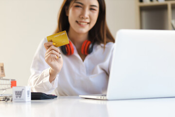 Woman holding credit card using laptop at home. Online shopping concept.