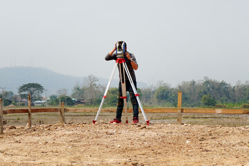 A surveyor looking through a theodolite at a construction site. A land surveyor works on a geodetic...