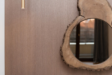 Fototapeta na wymiar new round mirror in a wooden frame on the wall