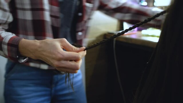 close-up of a hairdresser's hands braiding a pigtail