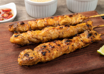 Chicken skewers over wooden board with farofa, lemon and pepper