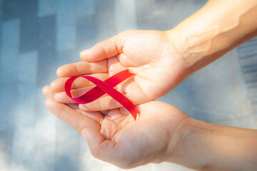 Women's hands hold the red ribbon, World AIDS Day Campaign.