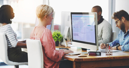 Hard at work in pursuit of success. Shot of a group of businesspeople working on computers in an...