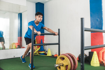 A young asian man uses a sled push at the gym. A prowler sled with weights. Full-body compound...