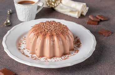 Dessert blancmange with chocolate sprinkled with chocolate chips on white plate