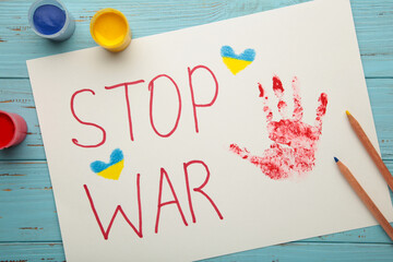 Inscription Stop war with baby handprint on blue background, conflict between Ukraine and Russia. No war, stop war, russian aggression. Ukrainian patriot.