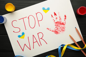 Inscription Stop war with baby handprint on black background, conflict between Ukraine and Russia. No war, stop war, russian aggression. Ukrainian patriot.