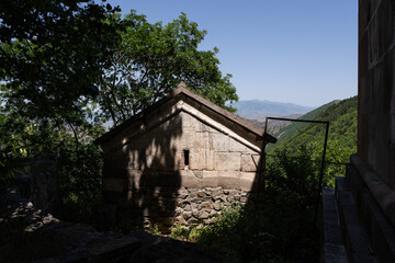 a small stone building high in the mountains, behind which there is a view of the mountains and above them a blue sky
