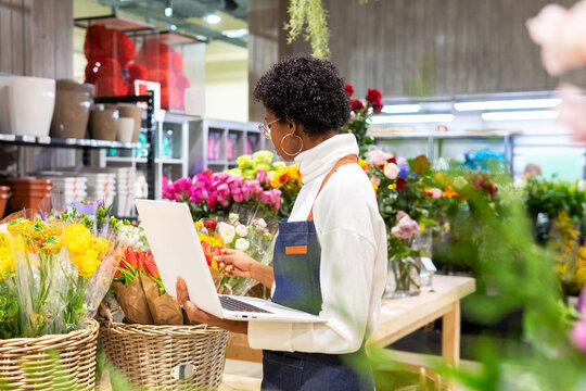 Black florist with laptop checking flowers