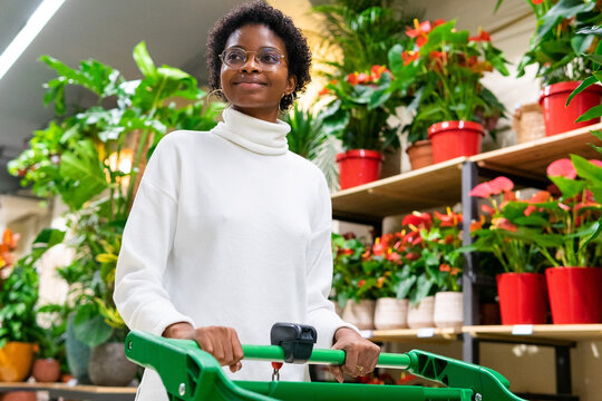 Black Woman With Shopping Cart In Floral Shop