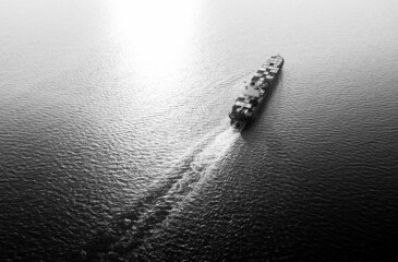 Aerial view container cargo ship in sea over sunlight background, black and white. - obrazy, fototapety, plakaty