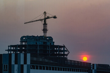 a construction crane on a tall building at sunset
