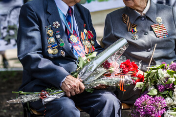Saying goodbye to a dear friend. Cropped image of two war veterans holding flowers at a funeral. - obrazy, fototapety, plakaty