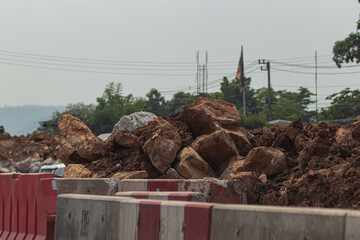 A pile of stones behind a roadside barrier