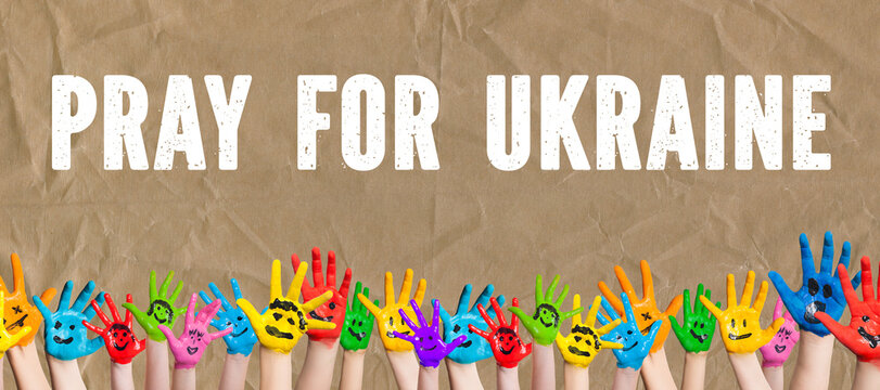 many hands and the message PRAY FOR UKRAINE on paper background
